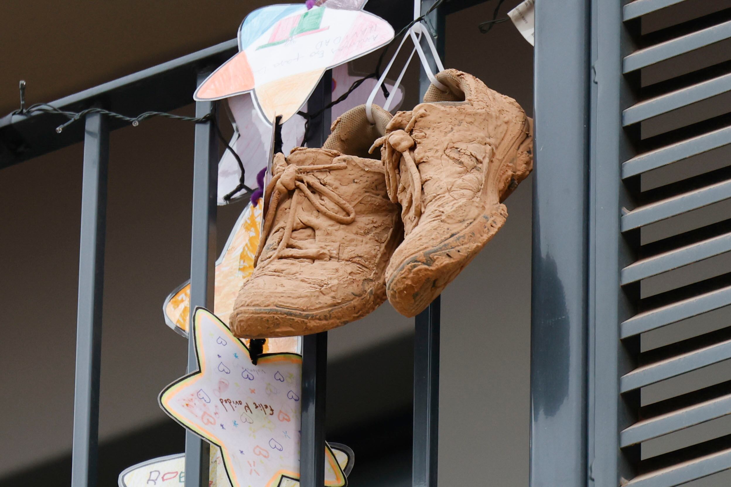 Un par de zapatillas de deporte cubiertas de barro cuelgan de un balcón en Paiporta. EFE/ Ana Escobar