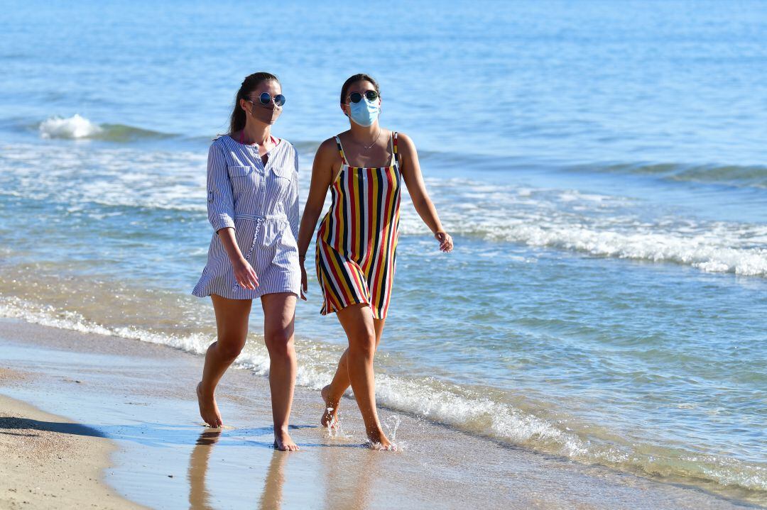 Dos mujeres jóvenes caminando por la playa de la Malva-rosa de València. 