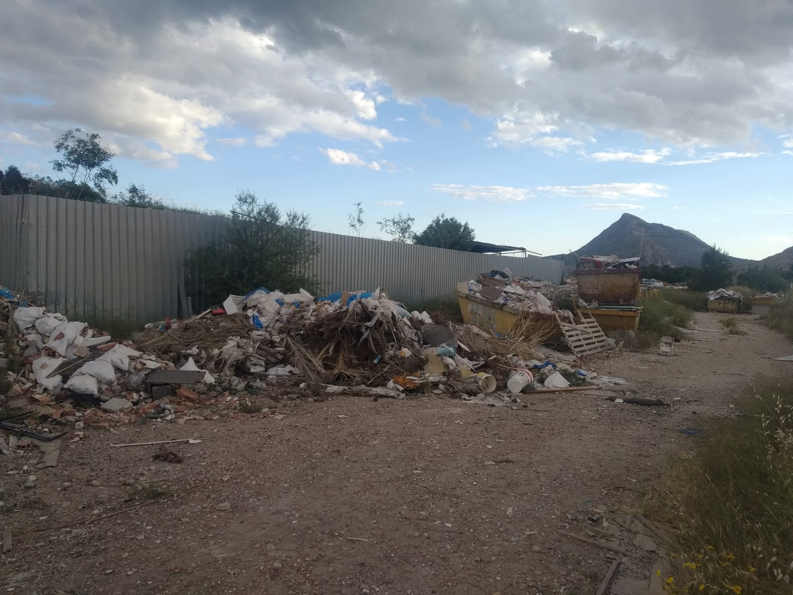 Residuos y escombros junto a la valla perimetral de la antigua escombrera