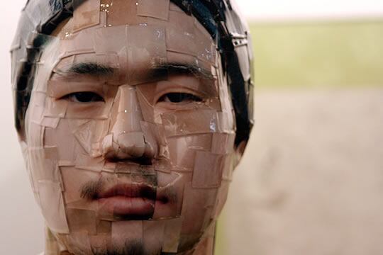 La imagen muestra un detalle de la estatua coreana hecha con papel fotográfico y barniz.
