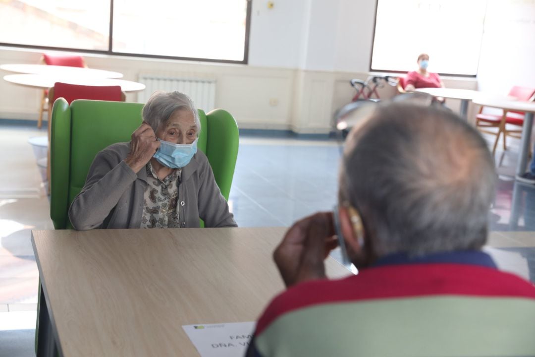 Un anciana residente recibe a un familiar durante la pandemia.