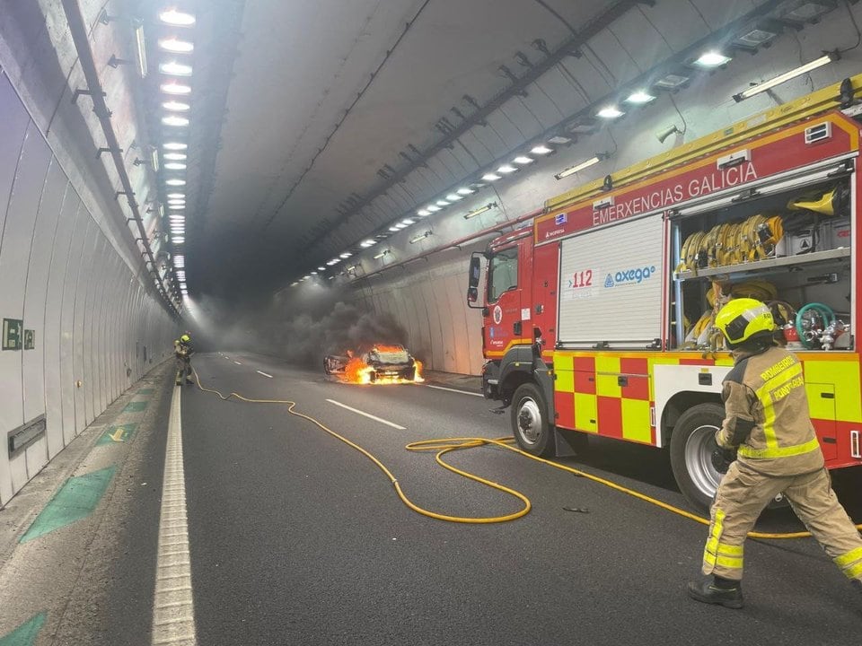 Imagen de los bomberos intentando sofocar el coche incendiado en el túnel de O Folgoso