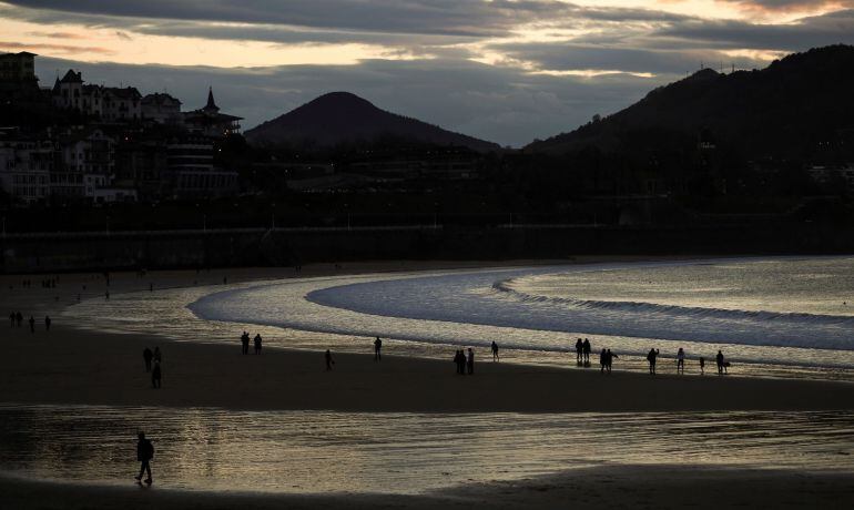 Vista de La Concha el jueves santo, en la que visitantes y donostiarras disfrutan del atardecer. 