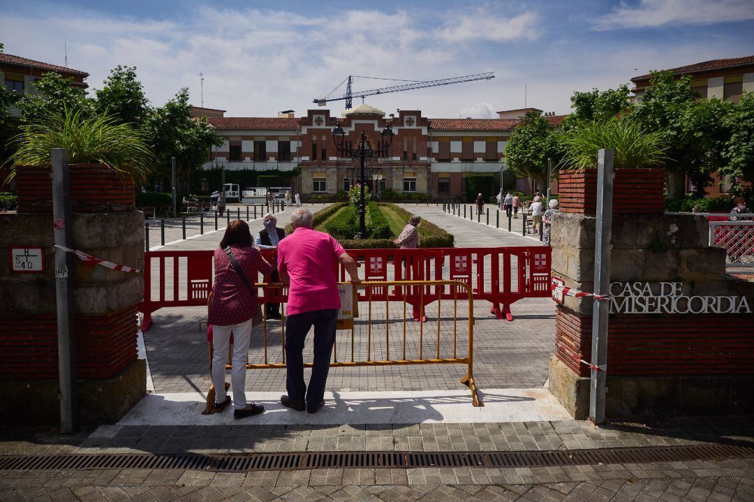 Una residente protegida con mascarilla de la ‘Casa de Misericordia’ habla con dos familiares en el exterior del centro donde han habilitado una zona de visitas, con una distancia de seguridad determinada y unas medidas higiénicas