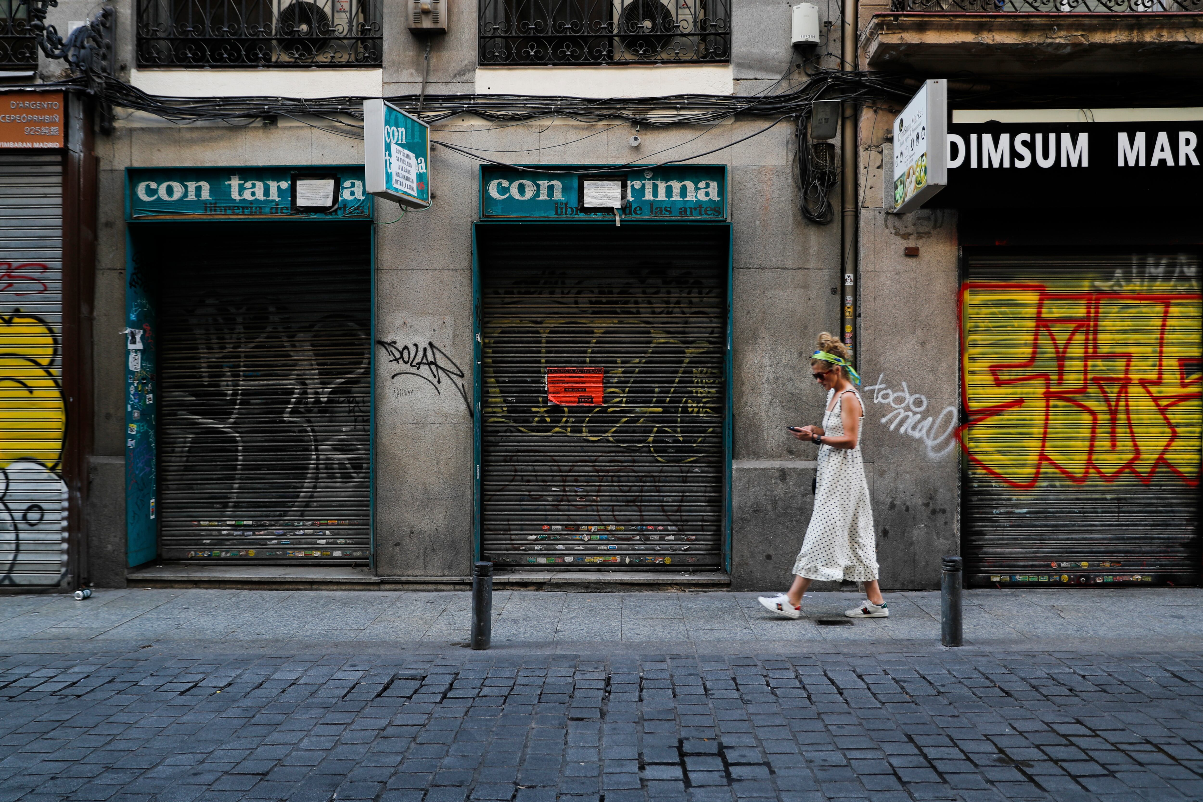 Una mujer pasa frente a unos locales cerrados