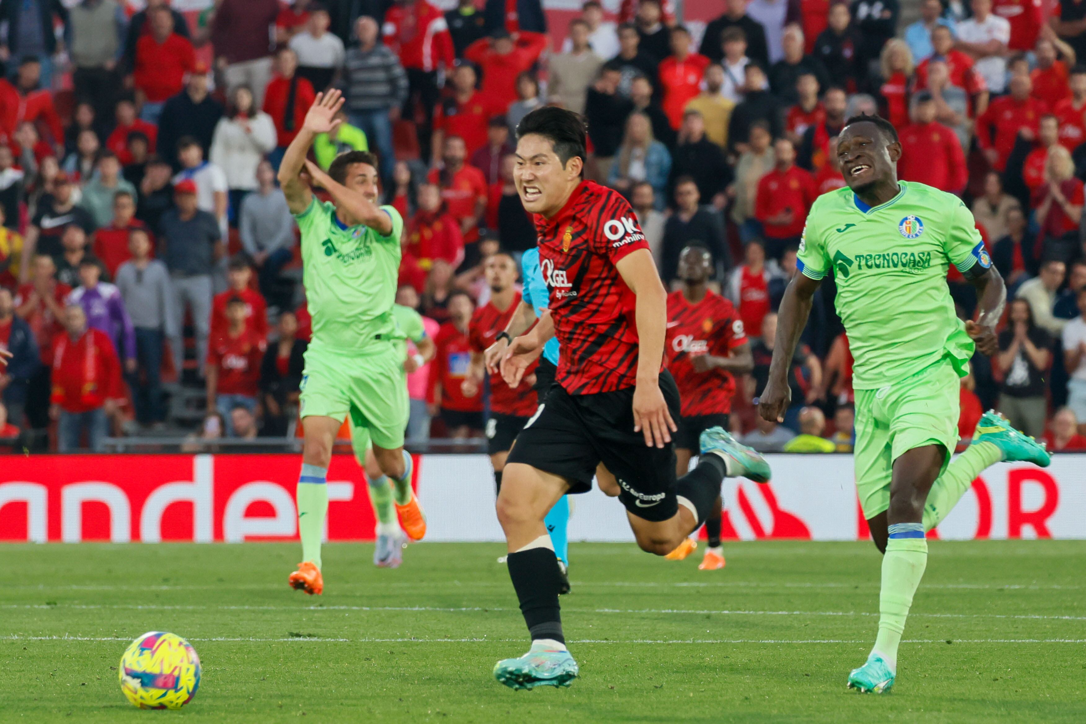 PALMA DE MALLORCA (ISLAS BALEARES), 23/04/2023. El centrocampista coreano del Mallorca, Kang-in Lee, conduce el balón perseguido por el defensa togolés del Getafe, Djene Dakoman, en la jugada que ha significado el tercer gol del equipo balear durante el encuentro correspondiente a la jornada 30 de primera división disputado hoy domingo en el estadio de Son Moix, en la capital balear. EFE/CATI CLADERA.
