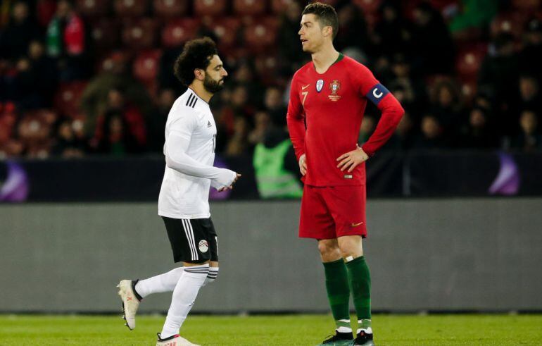 Mohamed Salah camina por delante de un Cristiano Ronaldo muy serio