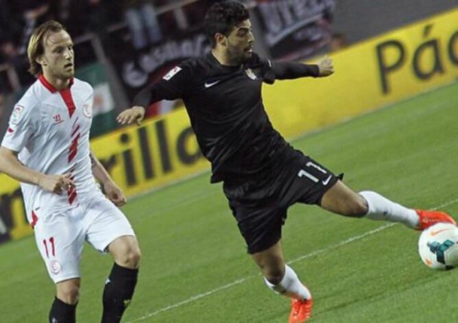 Carlos Vela defiende un balón ante la presión del sevillista Rakitic en el Sánchez Pízjuán. (EFE)