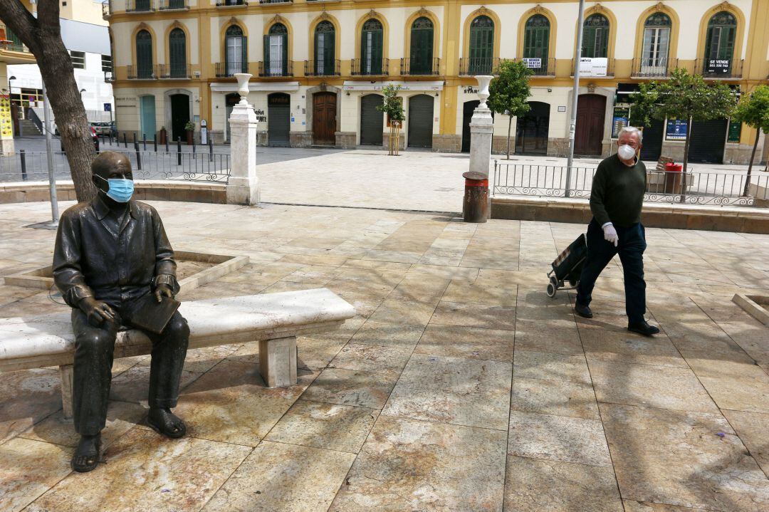 Una señor para delante de la estatua del pintor malagueño, Pablo Picasso, ubicada en la Plaza de la Merced de Málaga