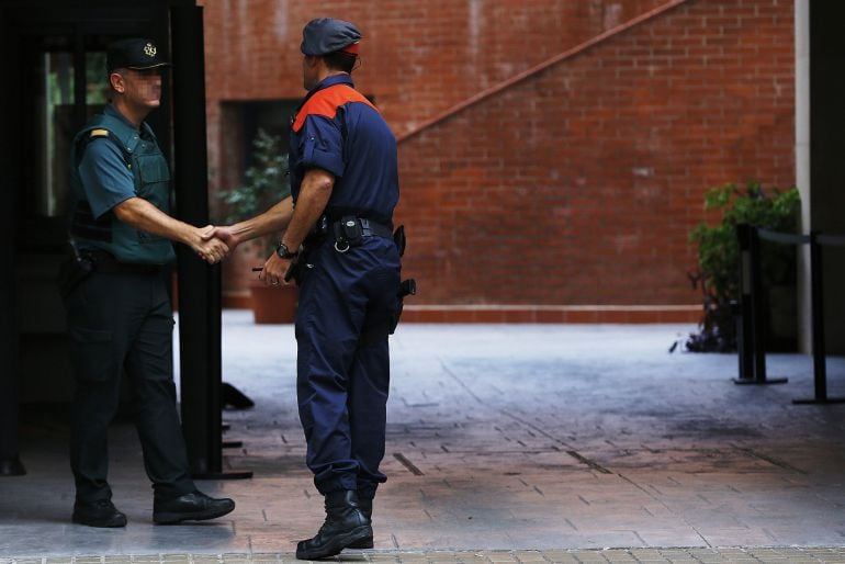 Un mosso d&#039;esquadra saluda a un guardia civil en la entrada de la caserna de Travessera de Gracia, en Barcelona.