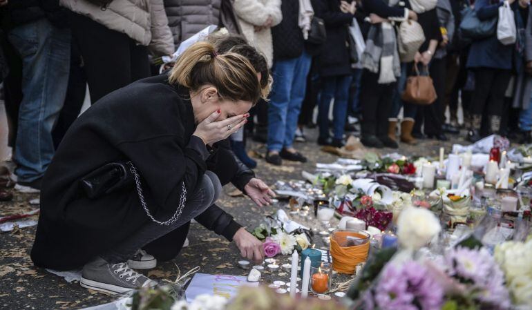 Varias personas colocan flores y velas en memoria de las víctinas de los atentados del pasado viernes