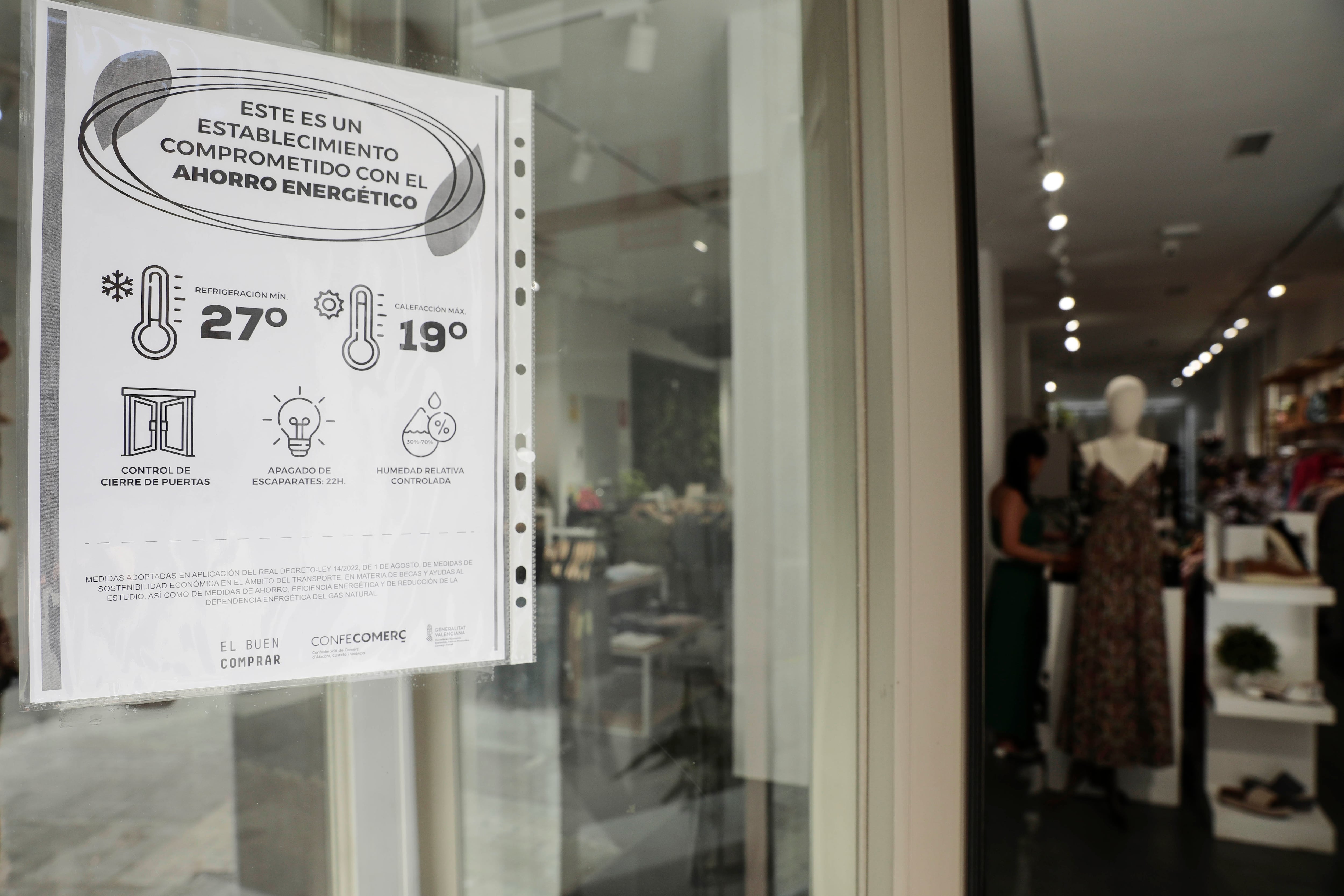 Un cartel informativo en una tienda de ropa de València, el 10 de agosto de 2022, sobre las medidas del plan de ahorro energético aprobado por el Gobierno el año pasado.