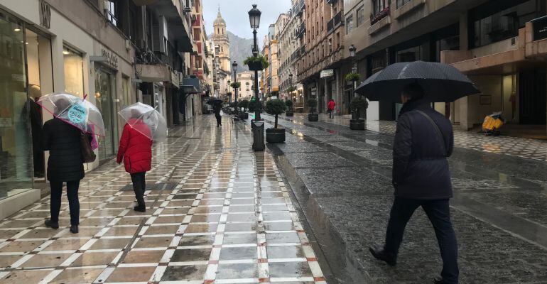 Varias personas con sus paraguas caminan este viernes por la calle Bernabé Soriano.