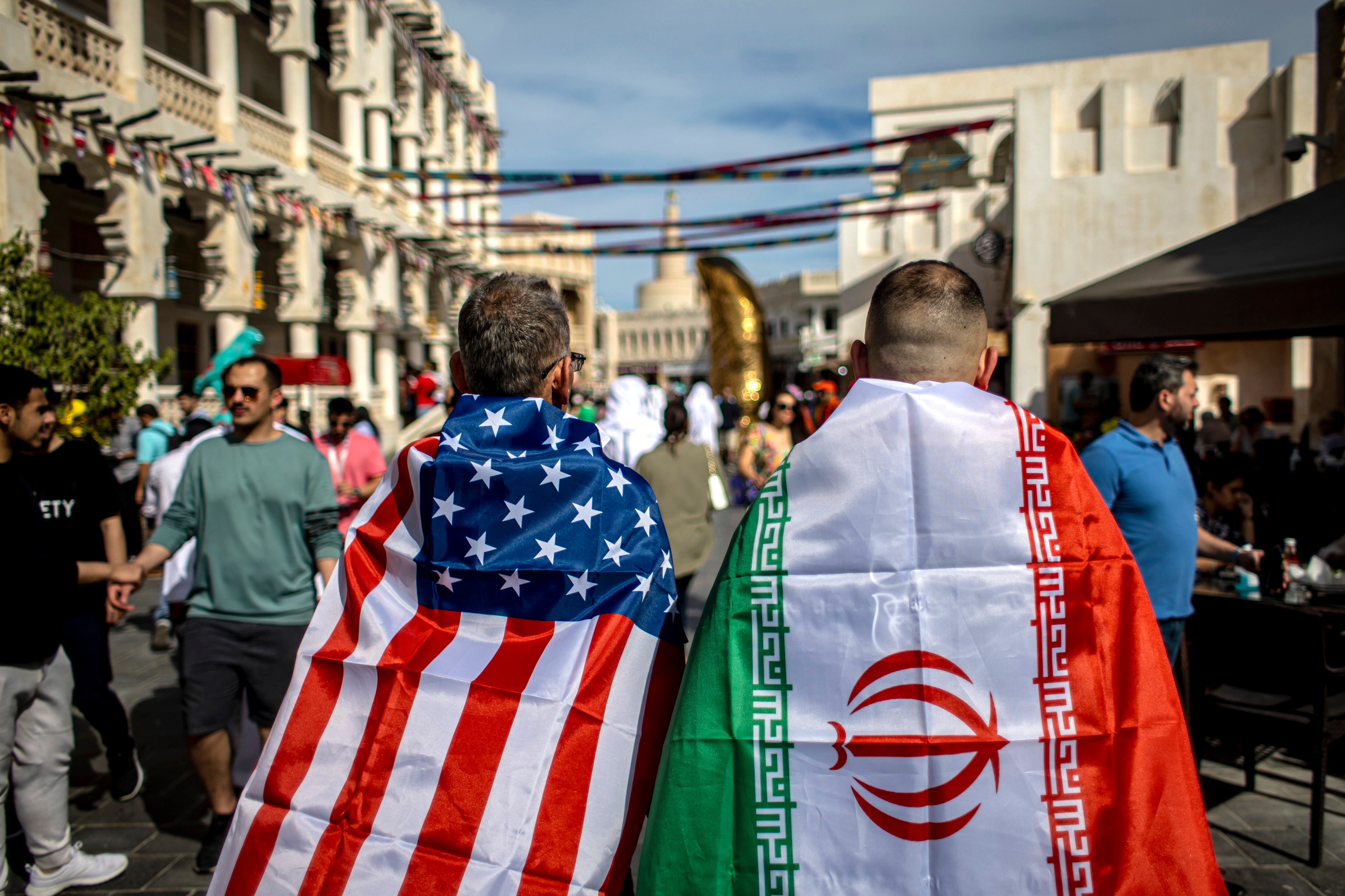 Dos aficionados de Estados Unidos e Irán caminan juntos por las calles de Doha, Qatar