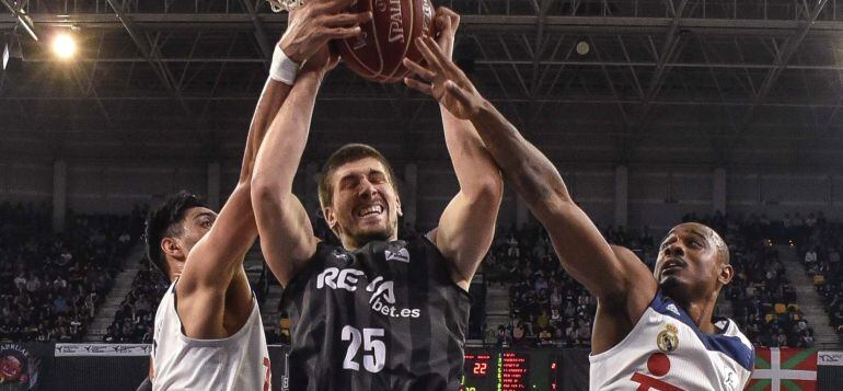 El pívot croata del Retabet Bilbao Basket Ivan Buva (c) lucha por el rebote con el base estadounidense del Real Madrid Dontaye Draper (d), durante el partido de la 12 jornada de la Liga ACB que se juega hoy en el Bilbao Arena