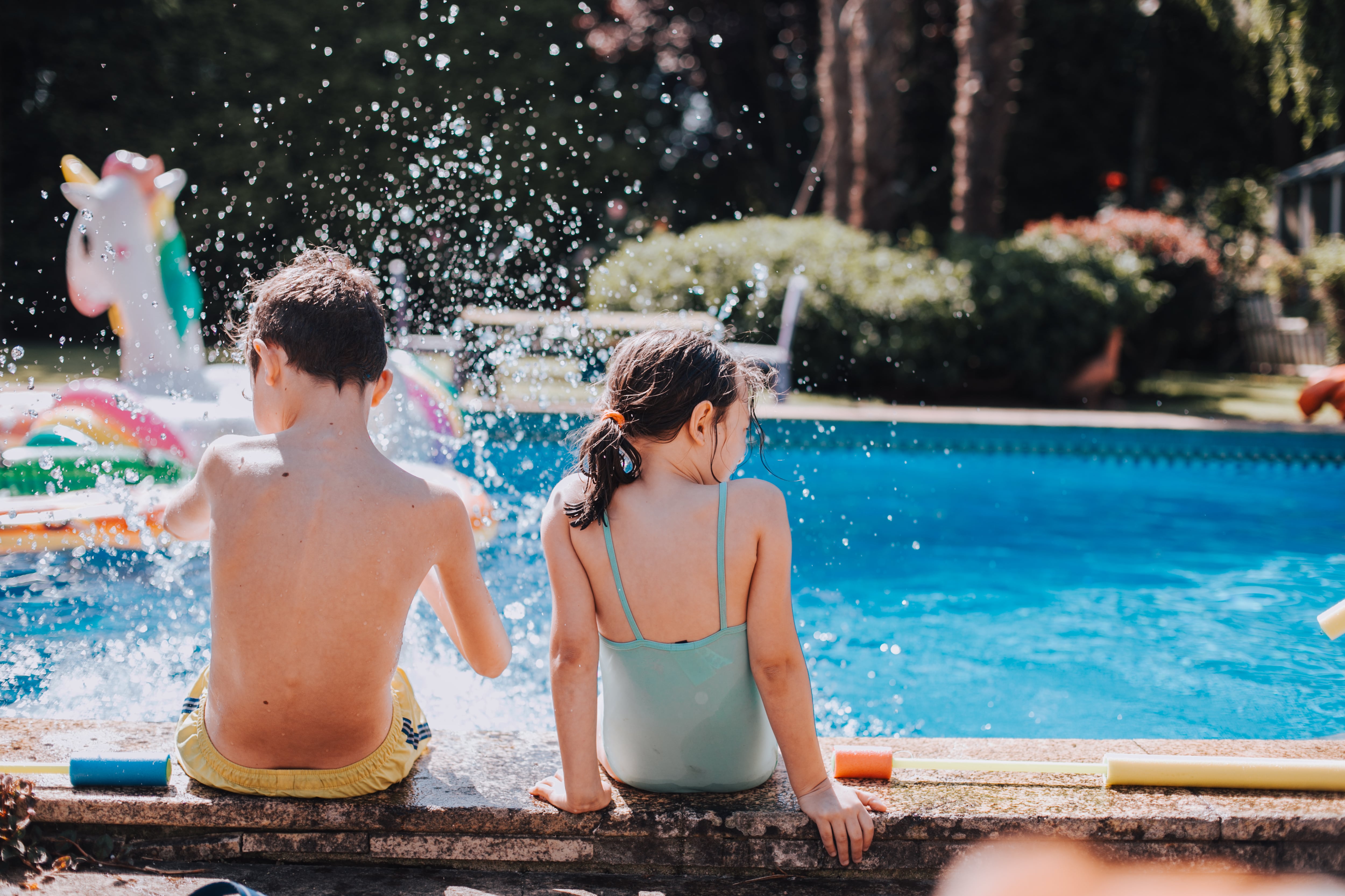 Niños salpicando en el borde de una piscina.