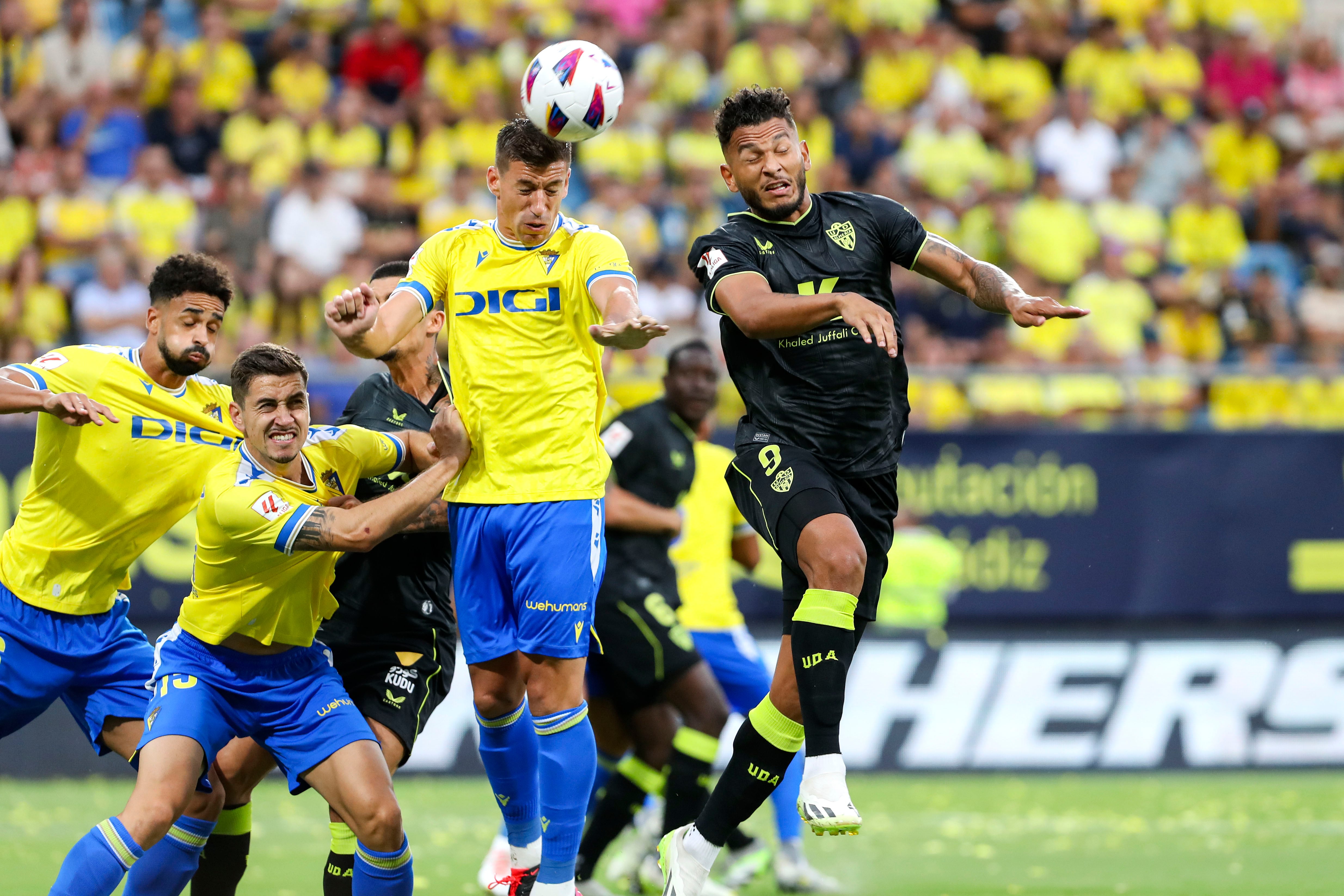 CÁDIZ, 26/08/2023.- El centrocampista del Cádiz Rubé Alcaraz (2-d) cabecea un balón ante Luis Suárez (d), del Almería, durante el partido de la tercera jornada de LaLiga entre Cádiz CF y UD Almería disputado este sábado en el estadio Nuevo Mirandilla. EFE/Román Ríos