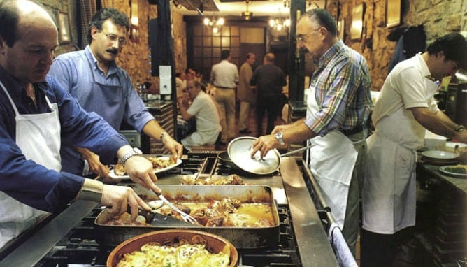 Varios hombres trabajan en la cocina de una sociedad gastronómica.