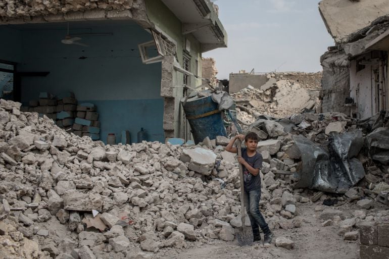 Un niño limpia restos de una vivienda en la ciudad de Mosul, el principal bastión del ISIS en Iraq 