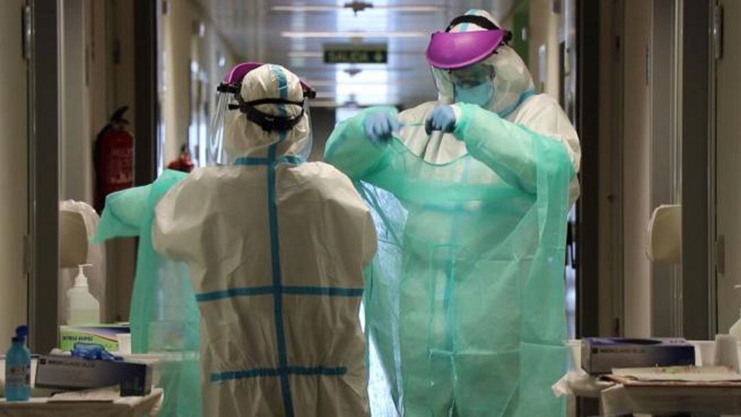 Dos sanitarios colocandose el material de protección.