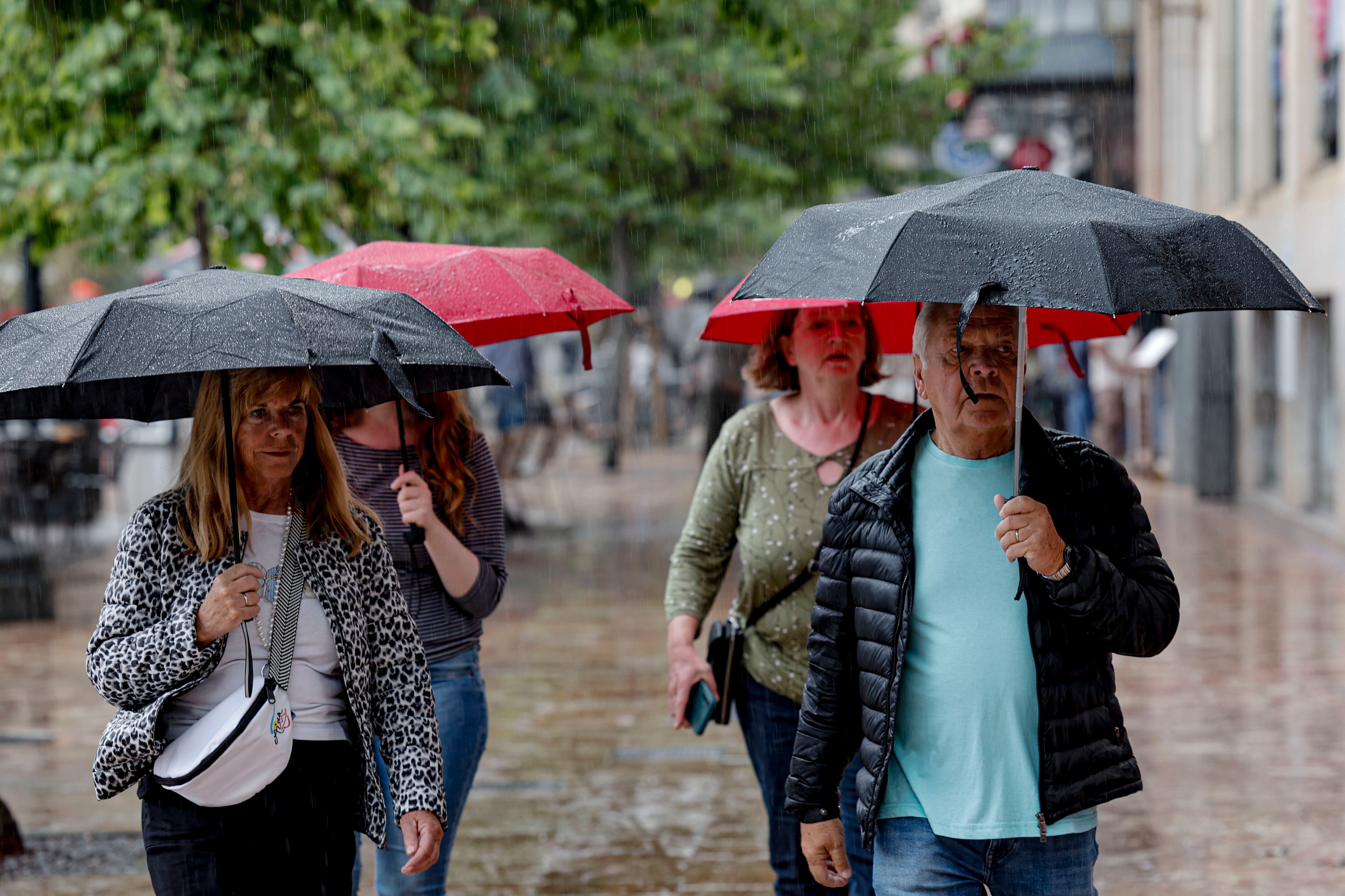 FOTODELDÍA GRAFCVA35894. VALÈNCIA, 01/05/2026.- El cielo de la Comunitat Valenciana presentará este viernes festivo cielo muy nuboso o cubierto, con chubascos acompañados de tormenta en Castellón y Valencia. En la imagen varios turistas se protegen de la lluvia mientras pasean por la plaza del Ayuntamiento de València. EFE/Manuel Bruque