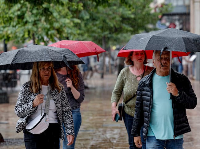 FOTODELDÍA GRAFCVA35894. VALÈNCIA, 01/05/2026.- El cielo de la Comunitat Valenciana presentará este viernes festivo cielo muy nuboso o cubierto, con chubascos acompañados de tormenta en Castellón y Valencia. En la imagen varios turistas se protegen de la lluvia mientras pasean por la plaza del Ayuntamiento de València. EFE/Manuel Bruque
