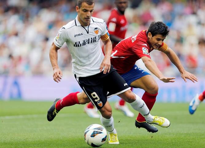 El delantero del Valencia Roberto Soldado avanza con el balón ante el defensa del Real Zaragoza Javier Paredes durante el partido correspondiente a la sexta jornada de Liga de Primera División