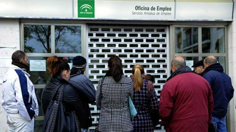 Varios ciudadanos esperan en la puerta de una oficina de Empleo.