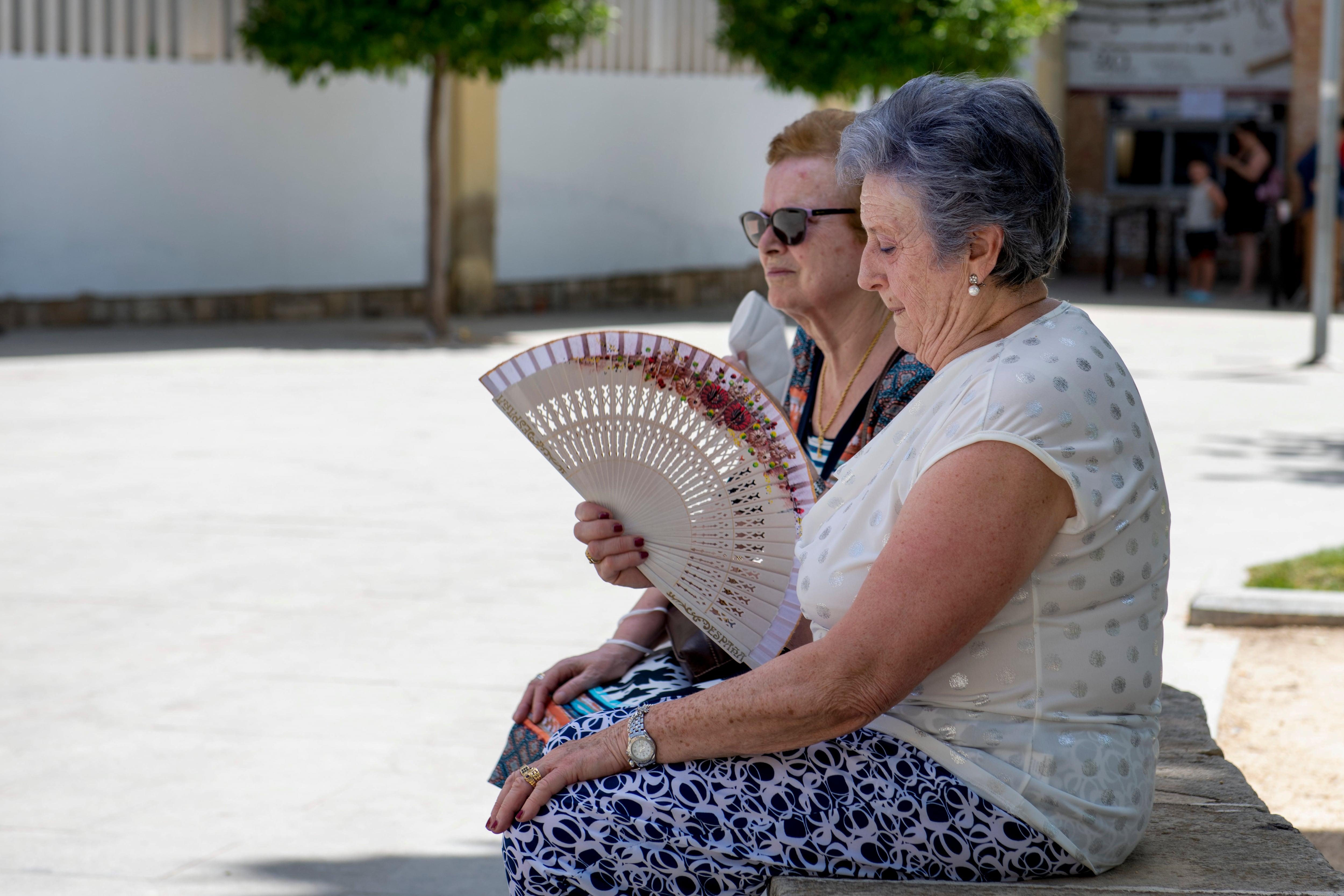 Dos señoras se abanican en la sombra en la alameda de Jaén.