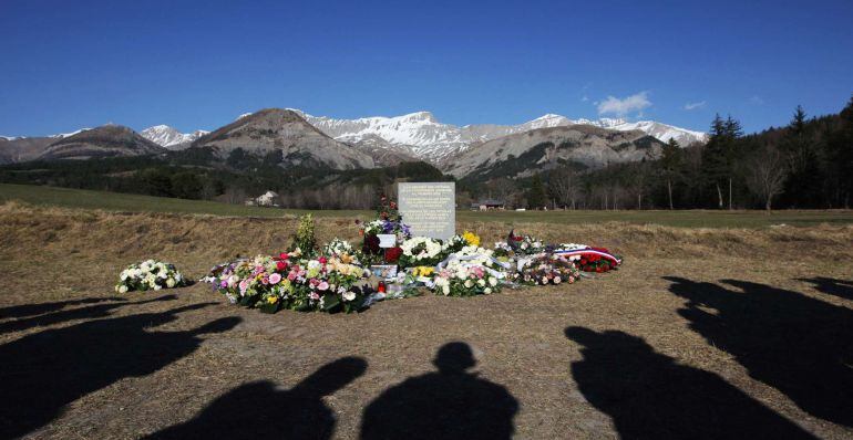 FILES - People cast their shadows as they stand near a stela commemorating the victims of the March 24 Germanwings Airbus A320 crash in the village of Le Vernet, southeastern France, on April 6, 2015 after a ceremony with victims' relatives. Relatives of those killed when a Germanwings flight was deliberately crashed into the French Alps are angry after the return of victims' remains was delayed for administrative reasons, their lawyer said on June 5, 2015. AFP PHOTO / JEAN CHRISTOPHE MAGNENET