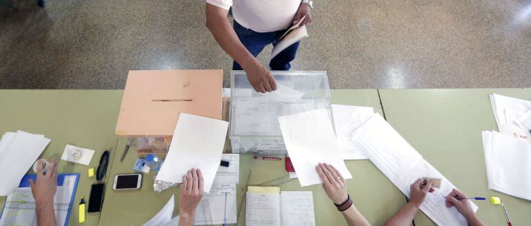 Un hombre deposita su voto en la urna de los diputados esta mañana en un colegio electoral