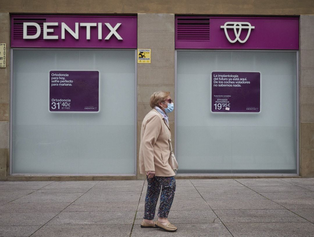 Una mujer paseas enfrente de una clínica de Dentix