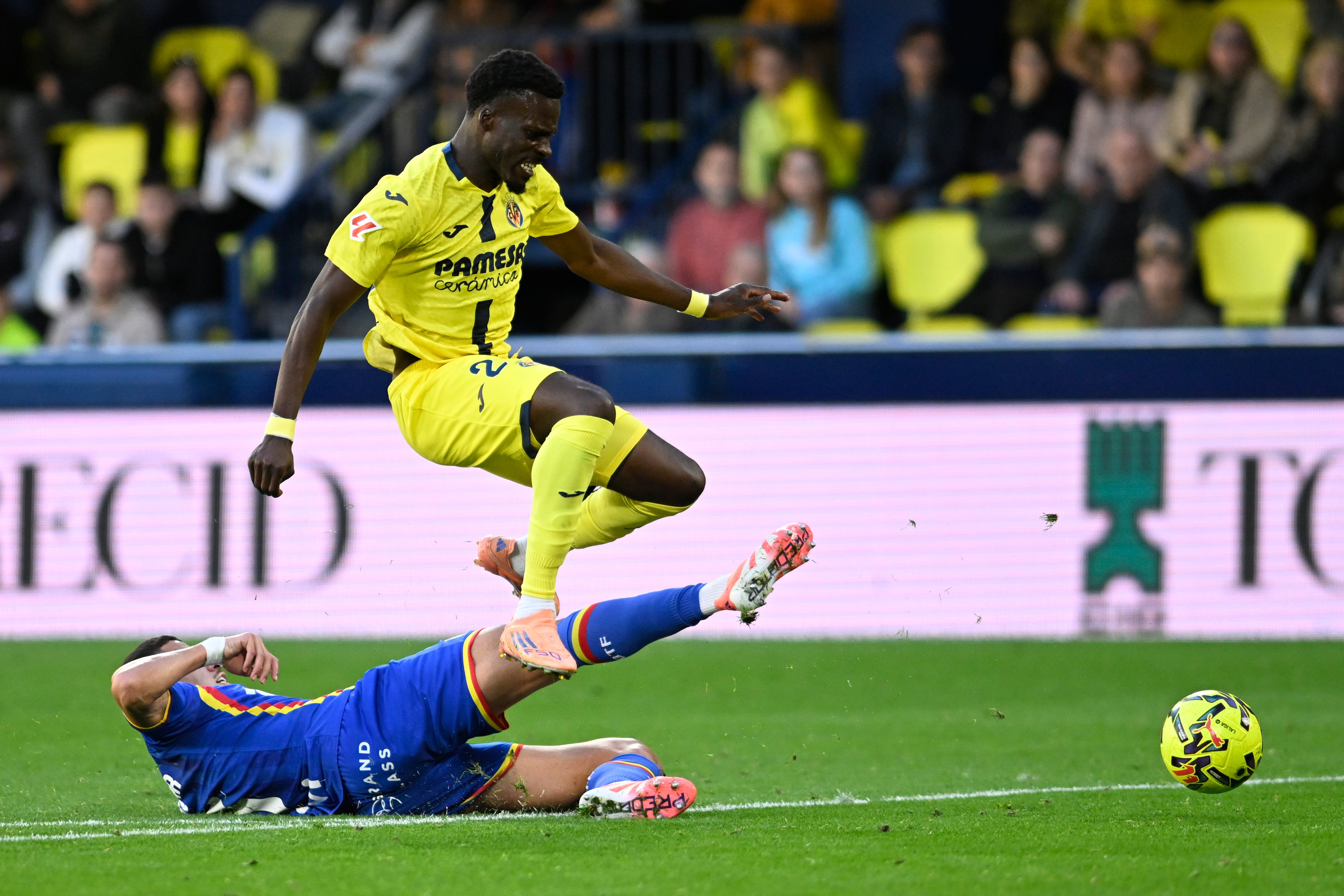 VILA-REAL (CASTELLÓN), 06/12/2025.- Tani Oluwaseyi (c) del VIllarreal, supera a Abdel Abqar, del GEtafe (i) durante el partido de la jornada 13 de LaLiga EA Sports entre el Villarreal y el Getafe, disputado este sábado en el Estadio de la Cerámica de Vila-Real (Castellón). EFE/ Andreu Esteban