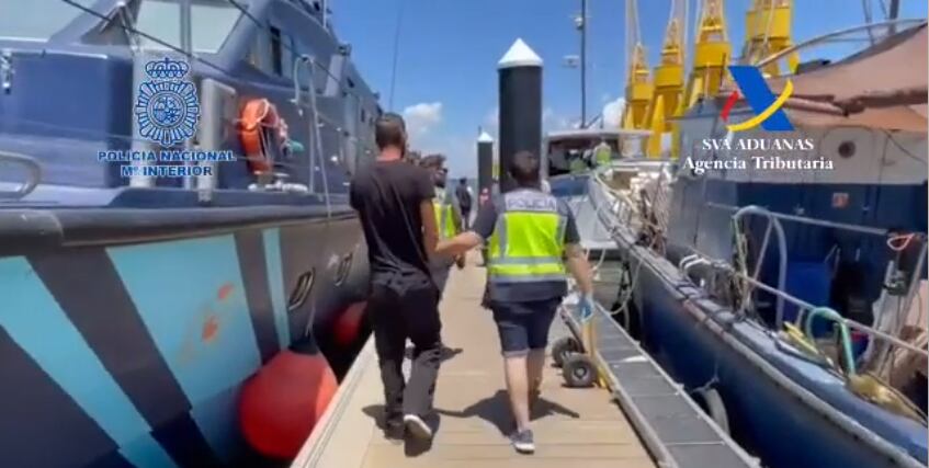 Uno de los detenidos junto a un agente de la Policía Nacional.