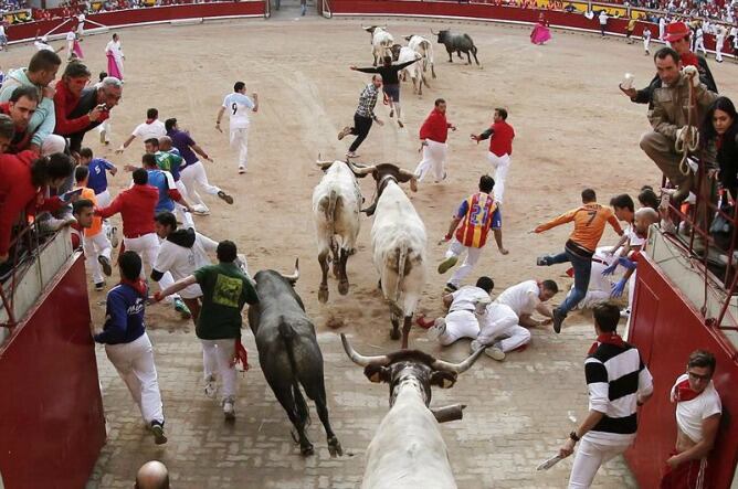 Varios mozos caen ante los toros de la ganadería extremeña de Adolfo Martín Andrés, en la entrada a la plaza de toros, durante el penúltimo encierro de los sanfermines.