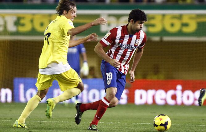 El centrocampista del Villarreal Tomás Pina pelea un balón con el delantero del Atlético de Madrid Diego Costa, durante el partido de la decimotercera jornada de liga en Primera División que se disputa esta noche en el estadio del Madrigal.