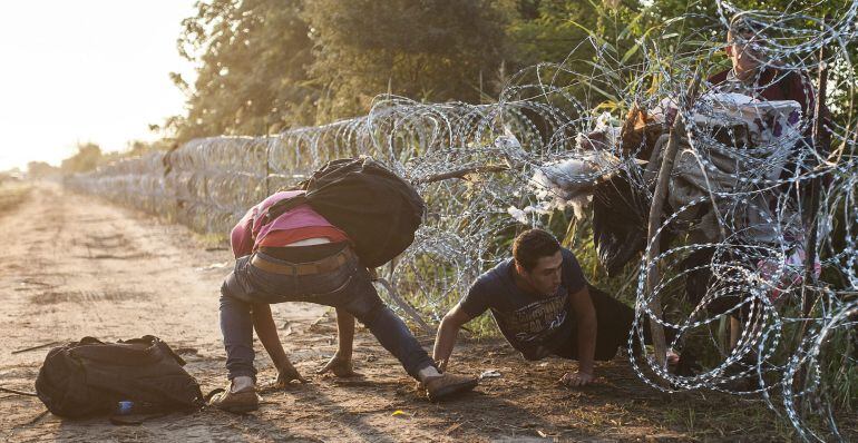 Varios inmigrantes pasan la alambrada en la frontera entre Hungría y Serbia