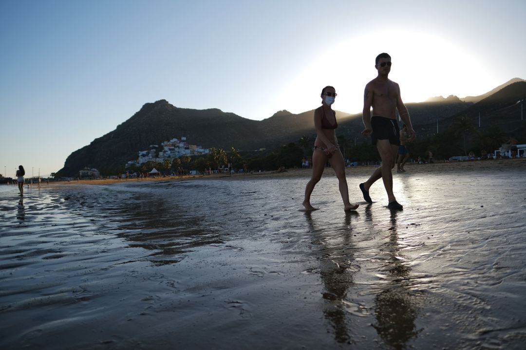 Dos personas pasean por una playa de las Islas Canarias