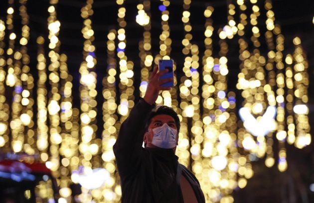 Una persona se fotografía con las luces de navidad del centro de Barcelona este lunes.