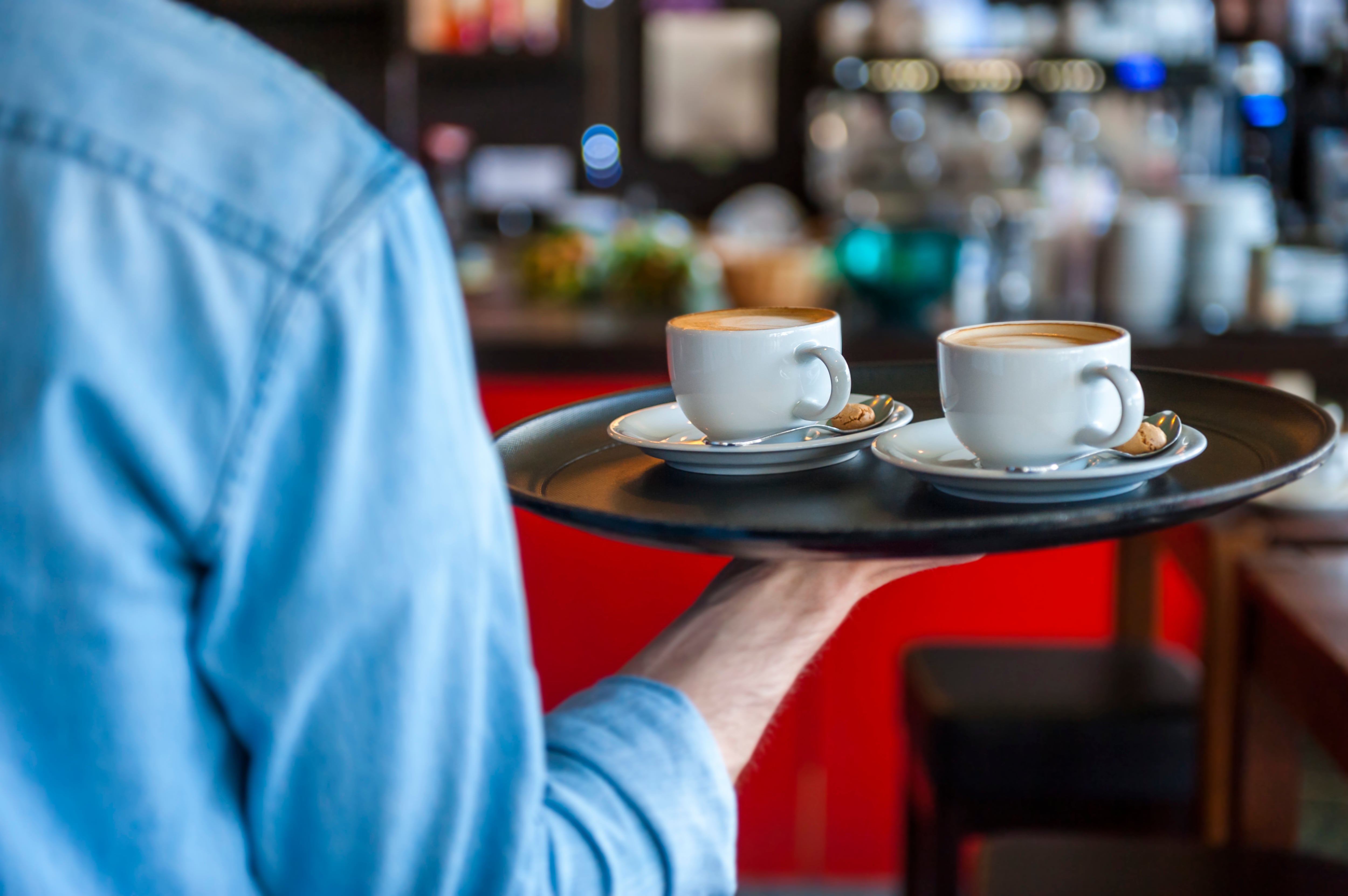 Camarero con una bandeja sirviendo un par de cafés