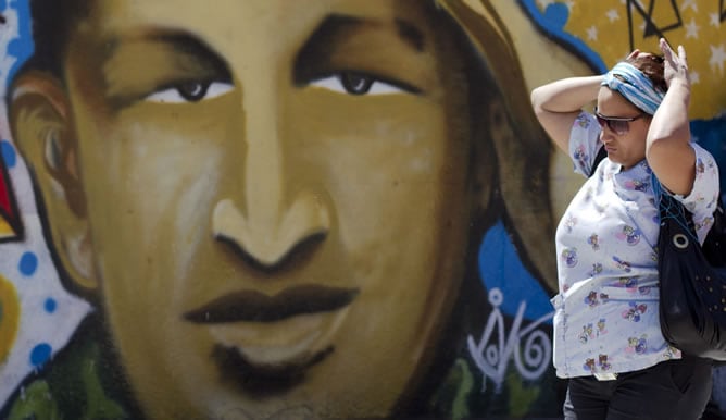 Una mujer pasea frente a un retrato de Hugo Chávez en las calles de Caracas