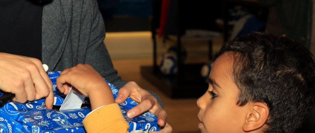 Un jugador del Deportivo entrega un regalo a un niño