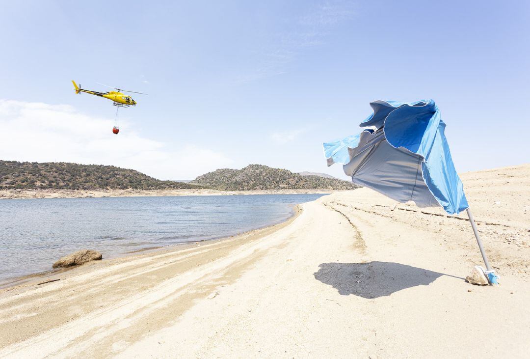 Un helicóptero sobrevuela el embalse del Burguillo, de donde coge agua para sofocar el cercano incendio de Sotillo de la Adrada