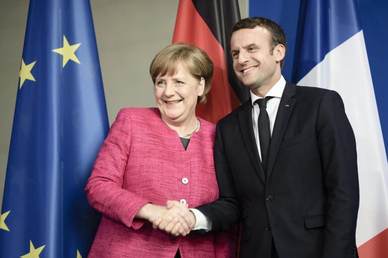 La canciller alemana Angela Merkel (i) y el presidente francés Emmanuel Macron (d) antes de la rueda de prensa tras su encuentro en la cancillería alemana en Berlín