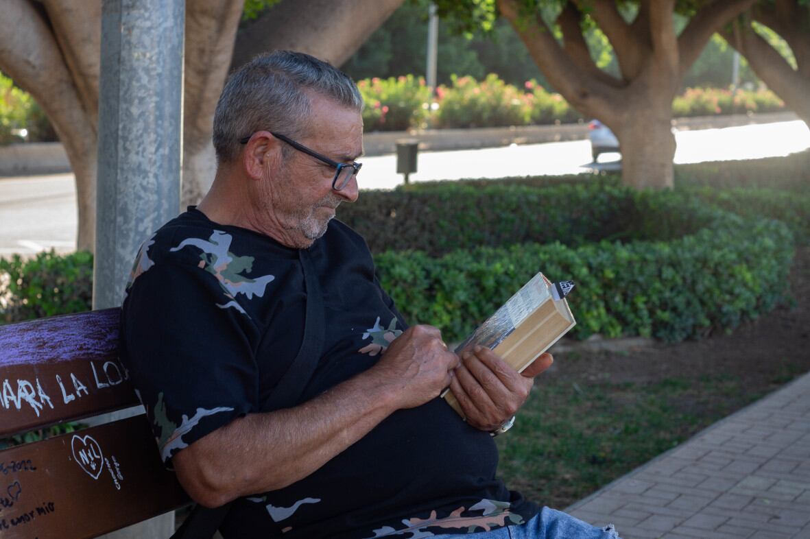 Uno de los vecinos lee un libro gratuito en la barriada Palma-Palmilla