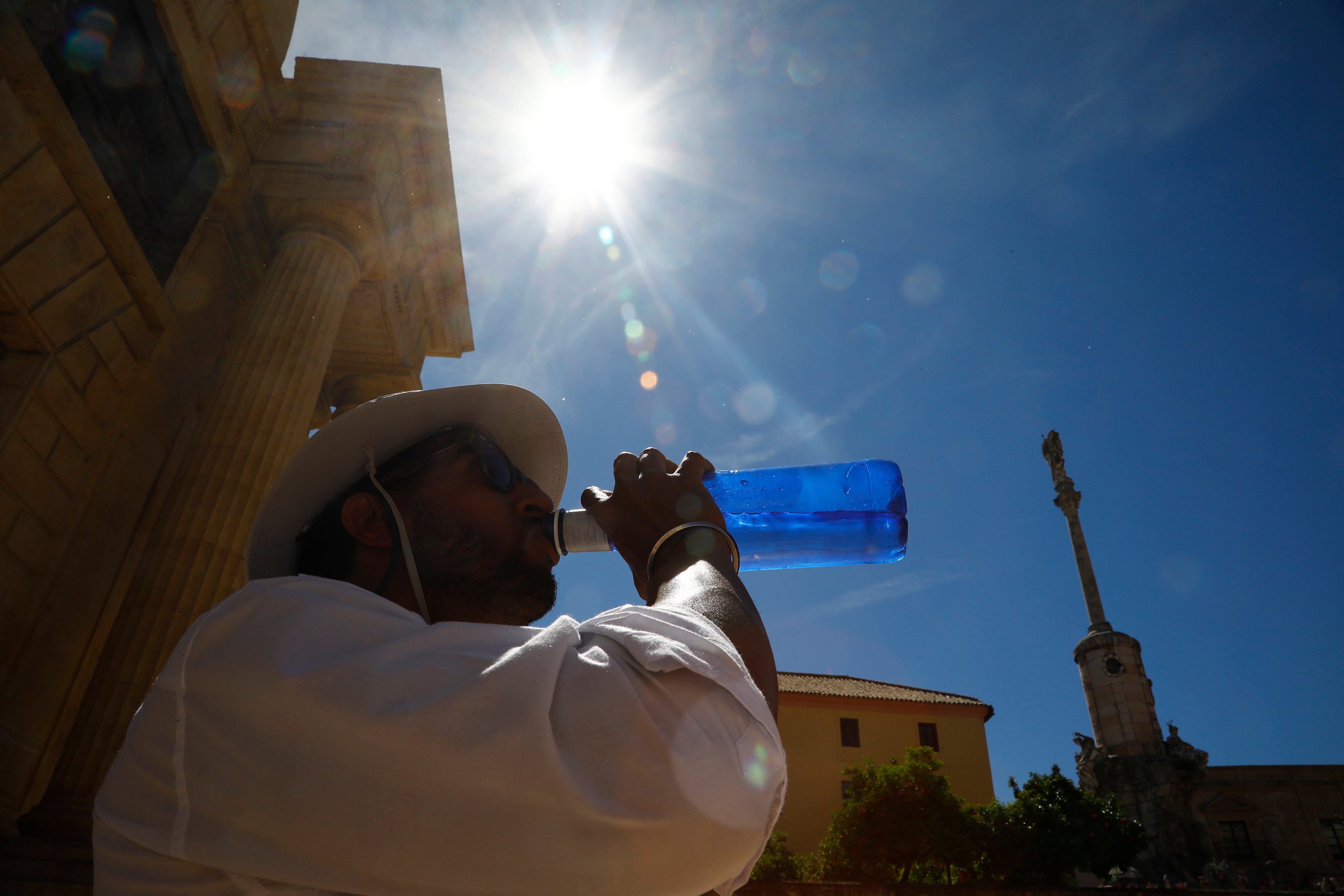 Un hombre bebe agua mientras camina por una zona turística de Córdoba