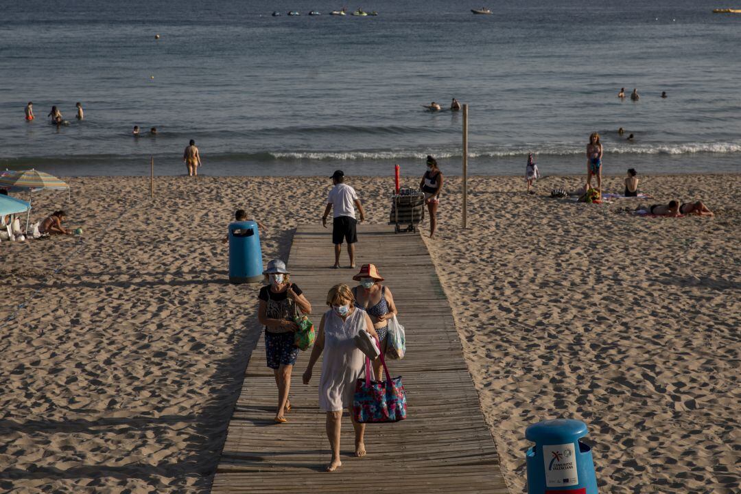 Varias personas salen de una playa de Benidorm, en Alicante.