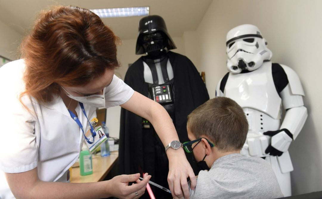 Un niño recibiendo la vacuna en el Hospital Valle del Nalón en Riaño, Asturias, ante la atenta mirada de Darth Vader