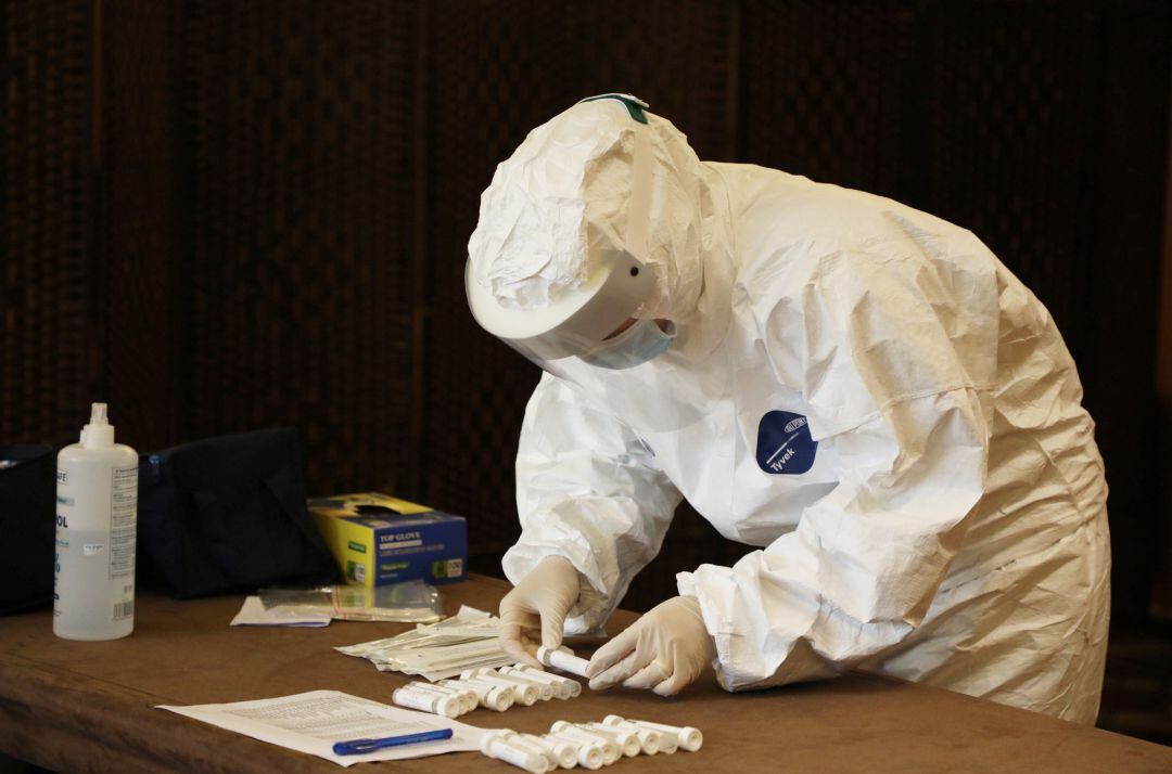 Un sanitario con un equipo de protección recoge muestras de pruebas PCR.