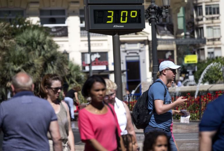 Varias personas pasan ante un termómetro urbano situado en la plaza del Ayuntamiento de Valencia mientras la Agencia Estatal de Meteorología presentaba el pronóstico del verano del 2016. 